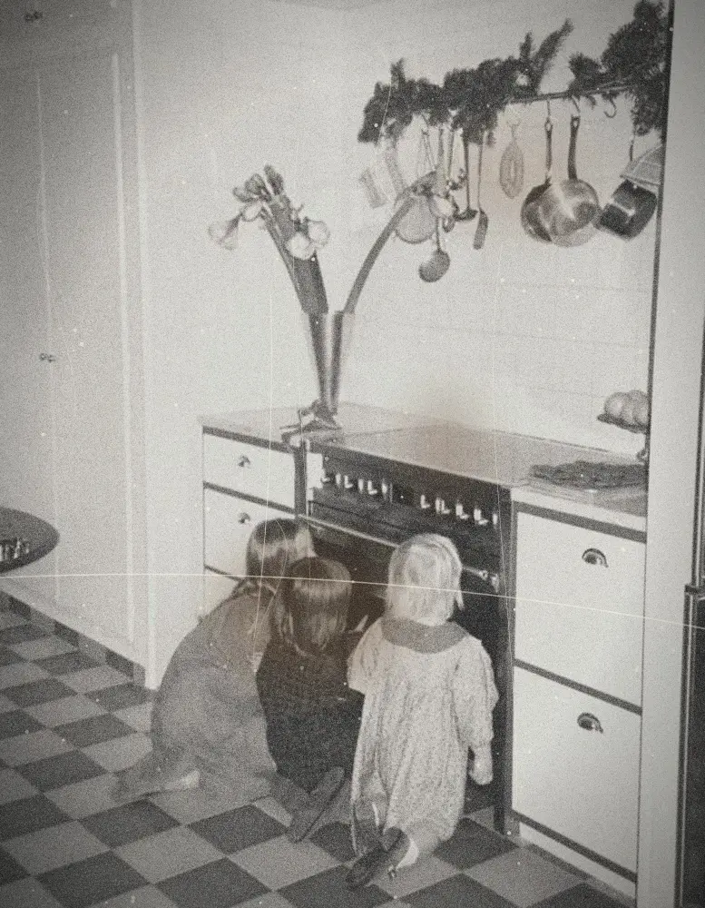 Trois enfants regardent à travers la vitre du four dans une cuisine