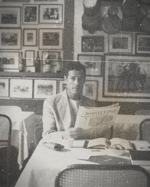Un homme lit le journal à une table de café