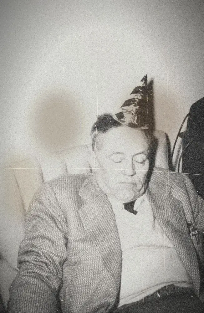 Un homme âgé endormi dans un fauteuil avec un chapeau de fête